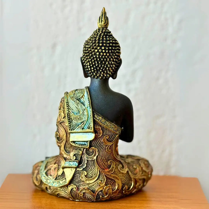 Estátua de Buda em resina, vista de costas, destacando detalhes dourados intricados no manto e na base da estátua.