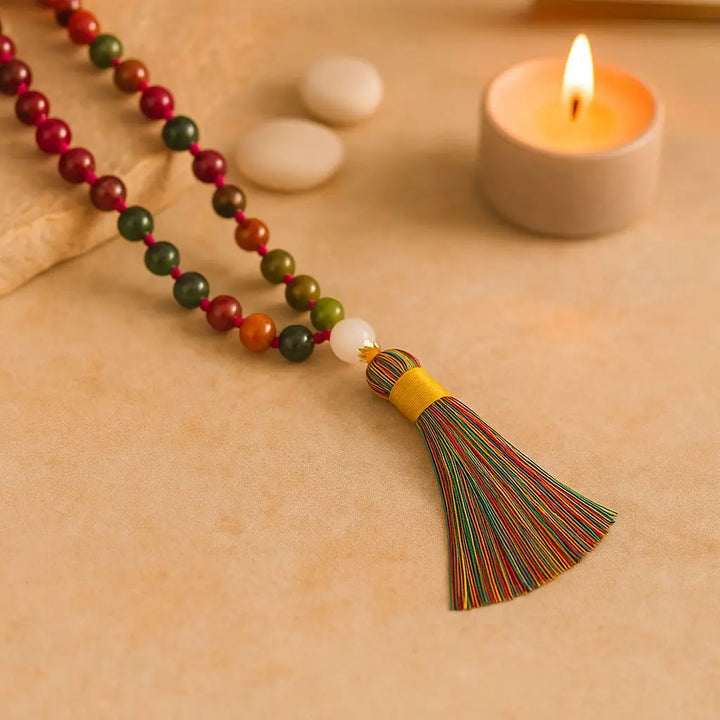 Japamala de turmalina colorida com tassel colorido e contas naturais – colar artesanal para meditação, exibido sobre superfície clara com vela acesa ao fundo