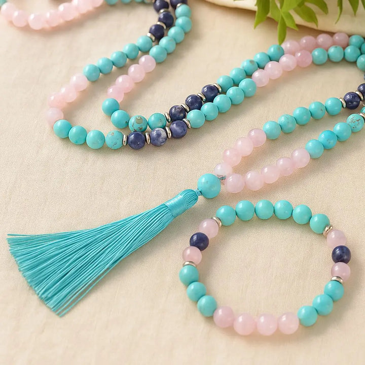 Detalhe das contas de Japamala e da pulseira em Quartzo Rosa, Turquesa e Lápis-Lazúli, com pingente em forma de fios azul turquesa, ideal para meditação.